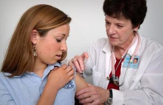 Eine junge Frau wird von einer Ärztin geimpft.