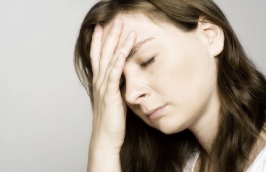 Blasse, junge Frau fühlt sich schlapp und erschöpft – ein Symptom von Eisenmangel.