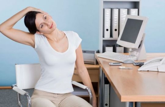 Büroyoga: Frau dehnt Nacken, sitzend auf Bürostuhl.