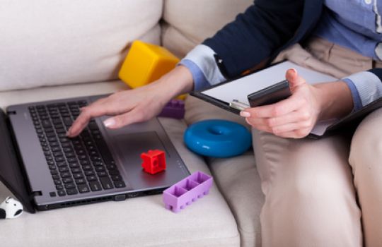 Person sitzt am laptop, umgeben von Spielzeug